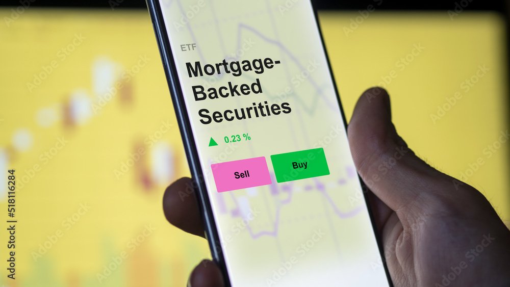 Investor's analyzing MBS the mortgage-backed securities etf fund on a screen. A phone shows the prices of mortgage backed securities ETF